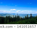 Scenic mountain view revealing lush forests and expansive blue skies on a sunny day 141051657