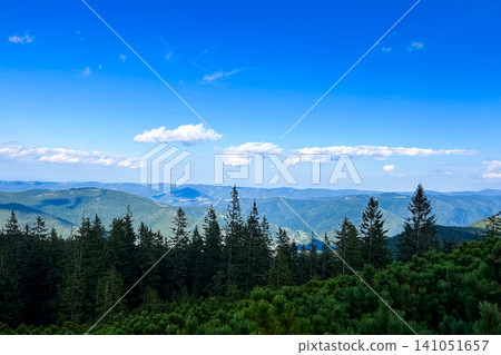 Scenic mountain view revealing lush forests and expansive blue skies on a sunny day Scenic mountain view revealing lush forests and expansive blue skies on a sunny day 141051657