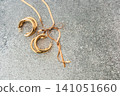 Elegant gold hoop earrings resting on a textured surface with a ribbon nearby 141051660