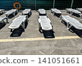 Empty sun loungers on a sunny deck by the water in a relaxing vacation setting 141051661