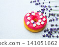 Colorful donut with pink icing and marshmallows beside fresh lavender flowers on a light background 141051662