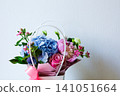 Beautiful floral arrangement in a basket with mixed flowers on a light background 141051664