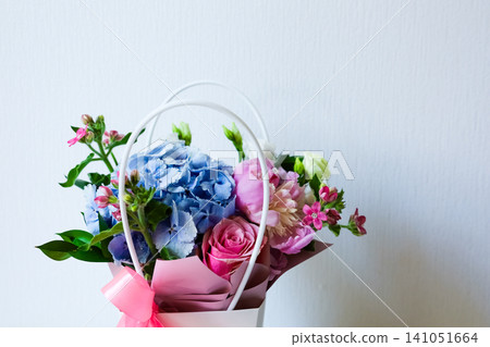 Beautiful floral arrangement in a basket with mixed flowers on a light background Beautiful floral arrangement in a basket with mixed flowers on a light background 141051664