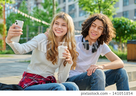 Happy teenagers making selfie video call on city street Happy teenagers making selfie video call on city street 141051854