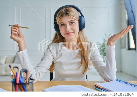 Teenage girl in headphones gesturing during video call 141051864