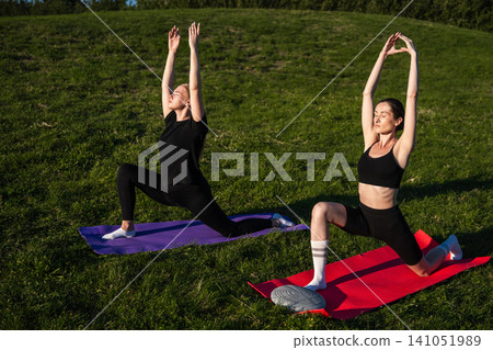 Women practicing yoga outdoors on a sunny day in a green park 141051989
