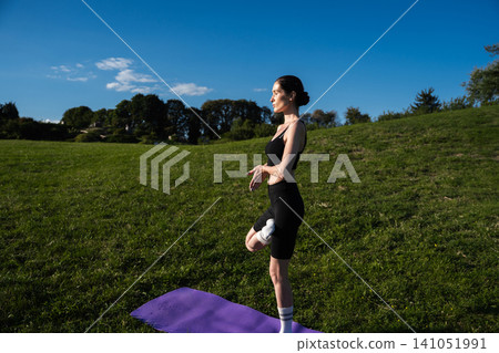 Practicing yoga in a serene park setting under a clear blue sky Practicing yoga in a serene park setting under a clear blue sky 141051991