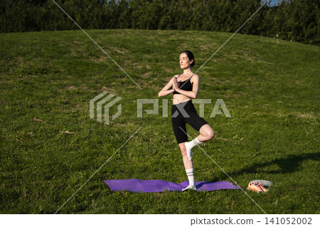 Balancing gracefully during outdoor yoga practice at sunset in the park Balancing gracefully during outdoor yoga practice at sunset in the park 141052002