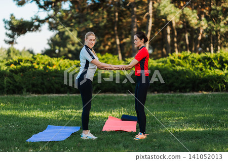 Women practicing exercise in park during sunny day Women practicing exercise in park during sunny day 141052013