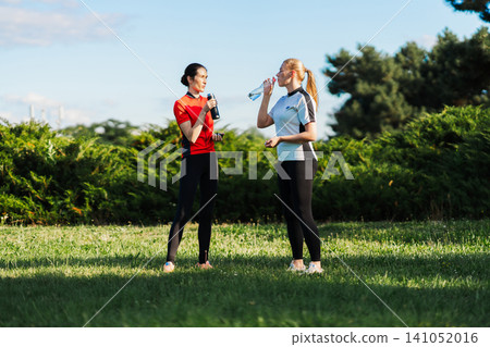 Two women stand in a grassy park Two women stand in a grassy park 141052016