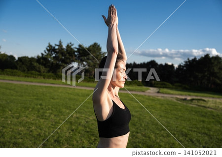 Woman practicing yoga outdoors under a clear blue sky in bright sunlight Woman practicing yoga outdoors under a clear blue sky in bright sunlight 141052021