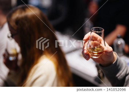 Enjoying whiskey tasting at a cozy bar with friends in the evening Enjoying whiskey tasting at a cozy bar with friends in the evening 141052096