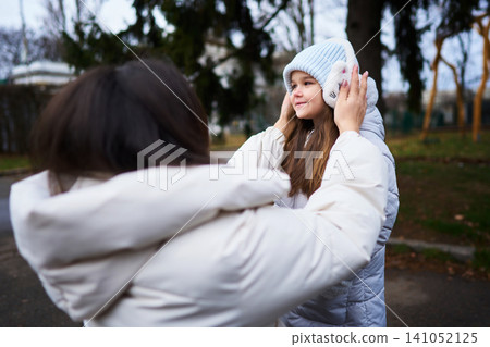 Girls playing outdoors in winter clothing on a chilly day in the park Girls playing outdoors in winter clothing on a chilly day in the park 141052125