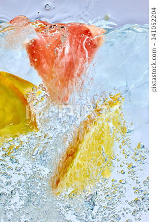 Grapefruit and lemon slices splashing in sparkling ice drink macro Grapefruit and lemon slices splashing in sparkling ice drink macro 141052204