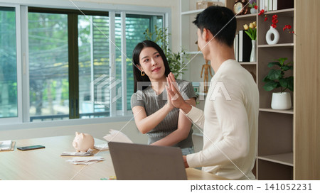 Happy Asian couple giving high five after calculating household budget at home Happy Asian couple giving high five after calculating household budget at home 141052231