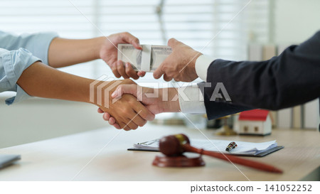 Close up of handshake and cash money exchange for bribe and corruption concept Close up of handshake and cash money exchange for bribe and corruption concept 141052252