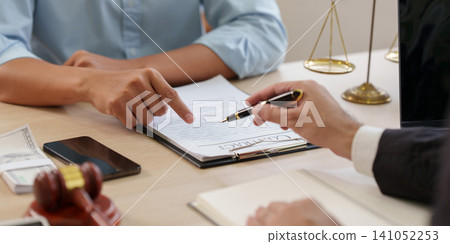 Cropped hands of lawyer and client discussing contract with gavel and scales of justice Cropped hands of lawyer and client discussing contract with gavel and scales of justice 141052253