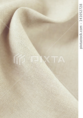 Close-up of beige linen fabric with soft folds and texture, natural organic fabric. 141052728
