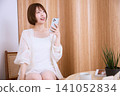 A young woman smiling while looking at her smartphone in a cafe. 141052834