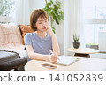 A young woman writing in a notebook in the living room. 141052839