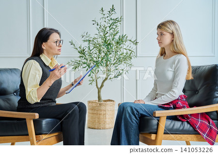 Professional female psychologist explaining solution to teenage girl at therapy Professional female psychologist explaining solution to teenage girl at therapy 141053226