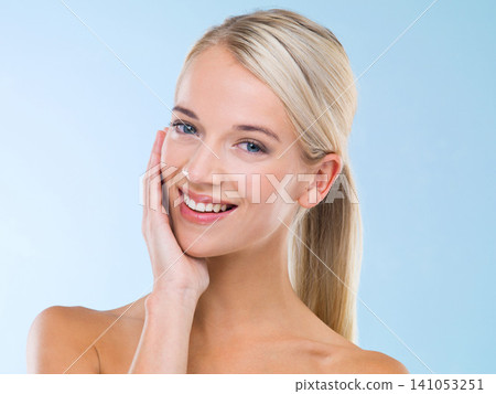 Beauty, portrait and woman with skincare cosmetics in studio with health, wellness and face routine. Smile, natural and female person with dermatology facial treatment isolated by blue background. Beauty, portrait and woman with skincare cosmetics in studio with health, wellness and face routine. Smile, natural and female person with dermatology facial treatment isolated by blue background. 141053251