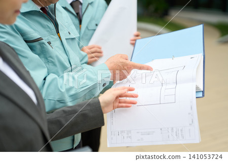 Asian construction workers checking the blueprints. Asian construction workers checking the blueprints. 141053724