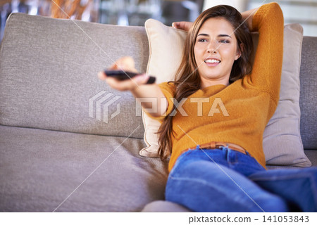Home, relax and woman with remote control, watching tv and happiness in a living room. Apartment, girl on a couch and person with entertainment or series with comedy movie and film with weekend break Home, relax and woman with remote control, watching tv and happiness in a living room. Apartment, girl on a couch and person with entertainment or series with comedy movie and film with weekend break 141053843