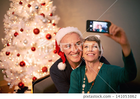 Christmas, selfie and senior couple with love, holiday and support in home with social media. Happy, retirement and marriage with smile and profile picture in house with celebration and santa hat Christmas, selfie and senior couple with love, holiday and support in home with social media. Happy, retirement and marriage with smile and profile picture in house with celebration and santa hat 141053862