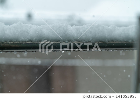 A close-up of snow piled on a clothesline and dripping water droplets on a snowy winter day. A close-up of snow piled on a clothesline and dripping water droplets on a snowy winter day. 141053953
