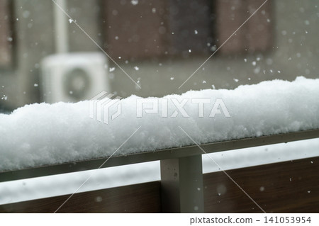 特寫鏡頭展現了冬季陽台欄桿上覆蓋著厚厚積雪的景象。 特寫鏡頭展現了冬季陽台欄桿上覆蓋著厚厚積雪的景象。 141053954