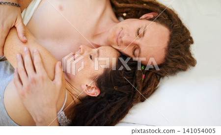 Sleeping, top view and couple hug in bed in home for peace, calm or relax to dream together in the morning. Above, man and woman cuddle to rest in bedroom for comfort or embrace for love in apartment 141054005