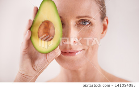 Cosmetic, avocado and portrait of woman in studio for health, wellness or natural facial routine. Skincare, beauty and mature person with organic fruit for dermatology treatment by white background. 141054083