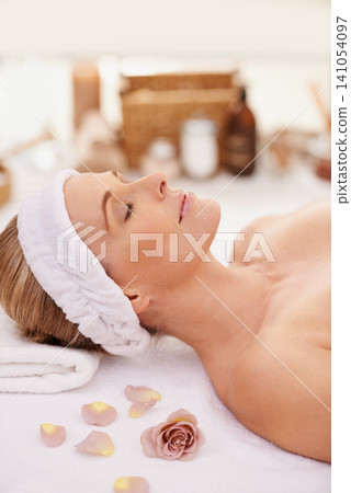 Woman, spa and rest for zen, peace and wellness with relaxation and calm. Lady, towel and massage table at resort, lounge or luxury parlor with rose for holistic body and skincare for detox and break 141054097