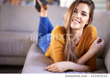 Portrait, home and relax with woman, smile or weekend break with confidence or peace in a living room. Face, girl lying on a sofa or apartment with person or calm with vacation, cheerful or happiness 141054220
