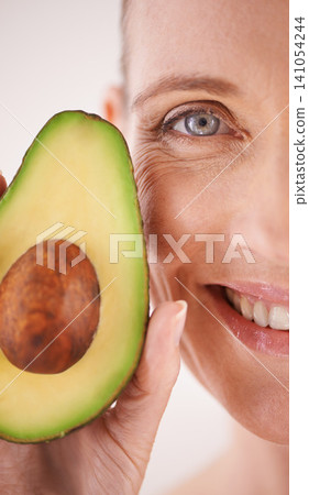 Skincare, avocado and closeup portrait of woman in studio for health, wellness or natural face routine. Smile, beauty or mature person with organic fruit for dermatology treatment by white background Skincare, avocado and closeup portrait of woman in studio for health, wellness or natural face routine. Smile, beauty or mature person with organic fruit for dermatology treatment by white background 141054244