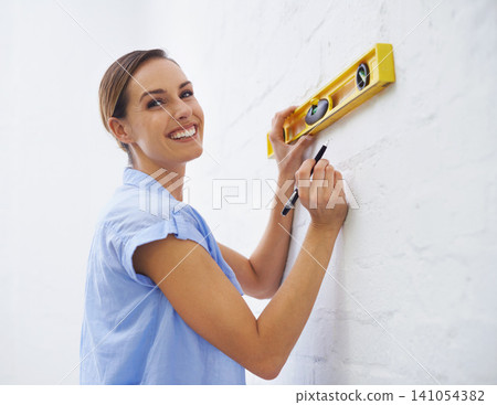 Level, wall and portrait of woman in house for interior design or renovation project and tools to align. Female person, remodeling and diy for home improvement or development and repair for upgrade 141054382