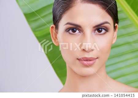 Face, woman and beauty with palm leaf, makeup and natural skincare with dermatology on white background. Organic, nature and eco cosmetics in portrait, clean with wellness and sustainable treatment Face, woman and beauty with palm leaf, makeup and natural skincare with dermatology on white background. Organic, nature and eco cosmetics in portrait, clean with wellness and sustainable treatment 141054415