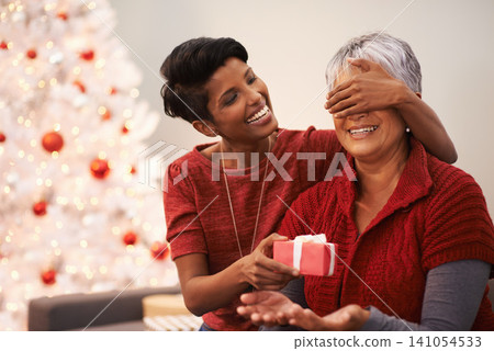 Senior, mother and daughter with surprise gift for Christmas, happiness with box and celebrate holiday at home. Festive season, decoration and present with happy people, family and bonding with love Senior, mother and daughter with surprise gift for Christmas, happiness with box and celebrate holiday at home. Festive season, decoration and present with happy people, family and bonding with love 141054533