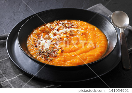 spiced sweet potato soup in a black bowl spiced sweet potato soup in a black bowl 141054901