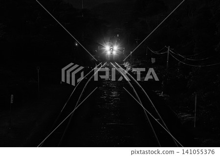 夜幕降臨，漆黑一片，一列火車在函館本線上行駛，車頭燈明亮地照射著。 141055376