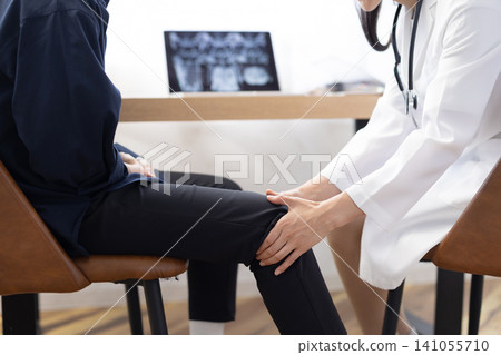 一位女醫生正在檢查病人膝蓋,鏡頭特寫她的雙手。 一位女醫生正在檢查病人膝蓋,鏡頭特寫她的雙手。 141055710