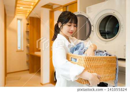 一位女士正在從烘乾機裡取出衣物。 一位女士正在從烘乾機裡取出衣物。 141055824