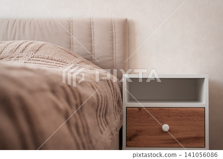 Modern bedside table next to cozy bed in minimalist bedroom interior Modern bedside table next to cozy bed in minimalist bedroom interior 141056086