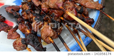 Grilled meat skewers coated in a smoky, char-kissed seasoning, served on a plate. Grilled meat skewers coated in a smoky, char-kissed seasoning, served on a plate. 141056174