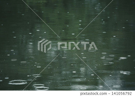 Raindrops falling on water and ripples on the water's surface Raindrops falling on water and ripples on the water's surface 141056792