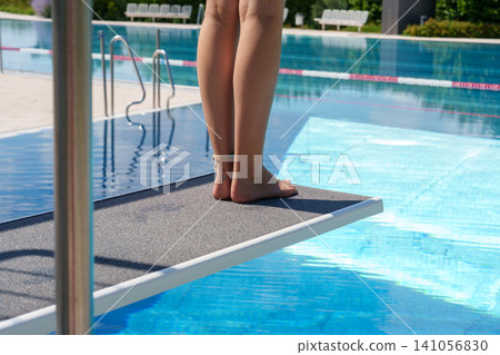 Child feet on diving board above blue pool water 141056830
