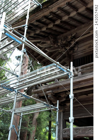 The main gate of a historic wooden temple, where metal scaffolding has been erected for restoration work. The main gate of a historic wooden temple, where metal scaffolding has been erected for restoration work. 141057492