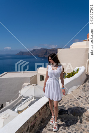 Full length of young woman in white dress walking in Oia Santorini Full length of young woman in white dress walking in Oia Santorini 141057561