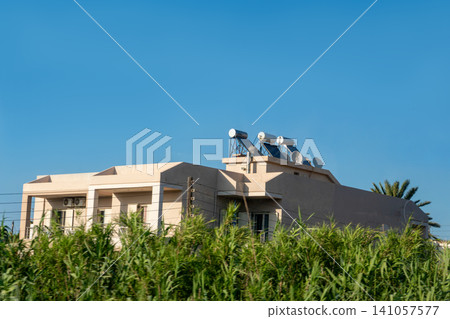 Modern residential building with solar panels and water heaters on roof Modern residential building with solar panels and water heaters on roof 141057577